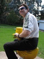 Un adulte joue sur un animal en bois.