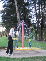 Deux enfants jouent sur un plateau qui tourne, aidés par un adulte.