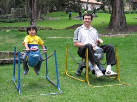 Un adulte et un enfant jouent chacun sur un animal en bois.