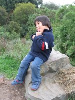 Un enfant assis sur une pierre tire la langue.