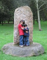 Deux enfants adossés contre une pierre posée sur une autre pierre.