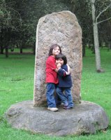 Deux enfants adossés contre une pierre posée sur une autre pierre.