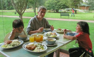 Une femme et deux enfants mangent à table.
