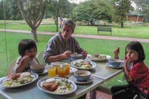 Une femme et deux enfants mangent à table.