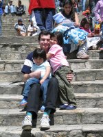 Un homme et deux enfants assis sur les marches d'un escalier.