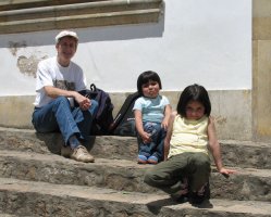 Une femme et deux enfants assis sur les marches d'un escalier.