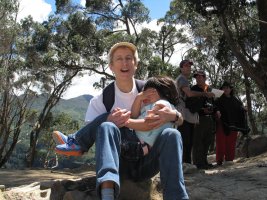 Une femme est assise sur un rocher et tient un enfant dans les bras.