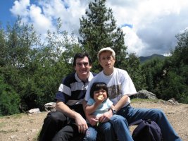 Deux adultes et un enfant sont assis sur une pierre.