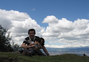 Un adulte et deux enfants sont assis dans l'herbe.