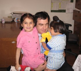 Un adulte et deux enfants dans les bras.