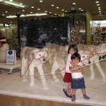 Deux enfants se tiennent debout devant des statuts de chiens.