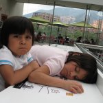 2 enfants sont assis au bord d'une table dans un a la tête sur la table.