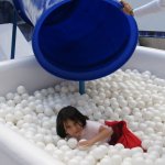 Un enfant dans un bain de balles blanches.