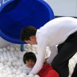 Un homme relève un enfant dans un jeu avec des balles blanches.