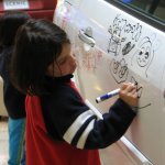 Deux enfants dessinent sur une voiture blanche.