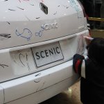 Un enfant dessine sur une voiture blanche.