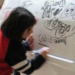 Un enfant écrit son prénom sur une voiture blanche.