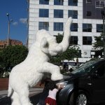 Un éléphant en statue et 2 enfants essayant de pousser une voiture.