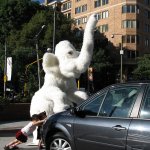 Un éléphant en statue et 2 enfants essayant de pousser une voiture.