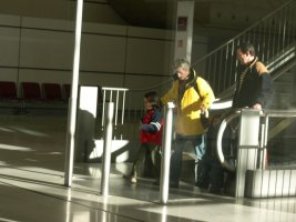 Une homme, une femme et deux enfants arrivent en bas de l'escalator.