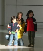 Deux enfants debout et une femme agenouillée.