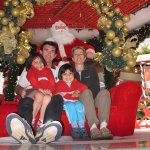 Un homme et une femme tenant chacun un enfant, assis dans un fauteuil de Père Noël.