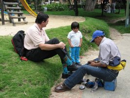 Un homme se fait cirer ses chaussures. Un enfant regarde la scène.
