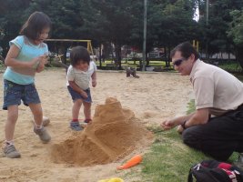 Deux enfants et une homme jouent dans le sable.