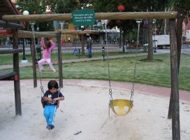 Dans un parc de jeux pour enfants, un enfant est assis sur une balançoire.