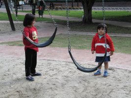 Deux enfants se tiennent debout auprès de balançoires.