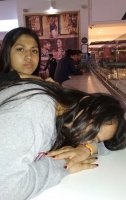 1 femme dormant sur une table et une autre accoudée sur la 1ère.