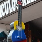 Guitare avec les couleurs de la Colombie, accrochée devant une devanture de magasin.