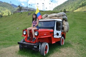 Femme assise sur le capot d'une jeep rouge.