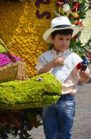 Petit garçon avec un sombrero à côté de fleurs.