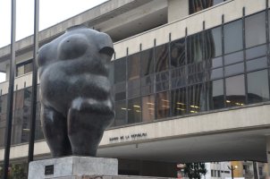 Statue de Botero représentant un corps nu sans tête devant un immeuble.