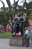 Statue de Botero représentant une femme nue assise avec son bébé assise sur son genou et taitant son sein doroit.