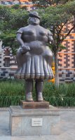 Statue de Botero représentant une femme aux seins nus se tenant debout.