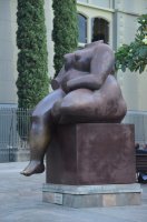 Statue de Botero représentant une femme nue assise et sans tête.