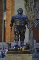 Statue de Botero représentant un homme musclé posé sur un homme allongé sur le ventre.