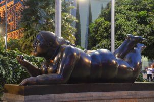Statue de Botero représentant une femme allongée et tenant une balle dans sa main droite.