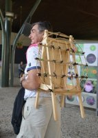 Homme portant sur son dos un support en bois pour porter des fleurs.