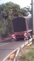 2 hommes à vélo tiennent l'arrière d'un camion.