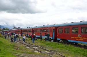 Wagons rouges le long d'une voie avec des personnes à côté.