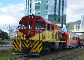 Train avec sa locomotive rouge et jaune et ses wagons rouge et bleu.