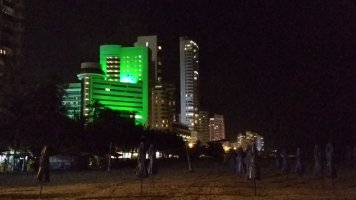 Immeuble éclairé vue de la plage la nuit.