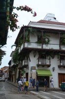 Coin de rue présentant une maison blanche avec ses balcons.