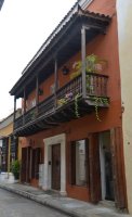 Façade d'une maison ocre avec balcon en bois.