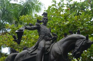 Statue d'un homme à cheval avec des pigeons sur sa tête et des bras.
