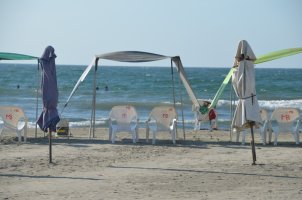 2 parasols fermés, 1 parasol ouvert, tendu sur 2 chaises, le tout sur la plage.