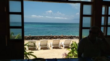 La mer au travers de la porte du restaurant. La terrasse abrite les transats.